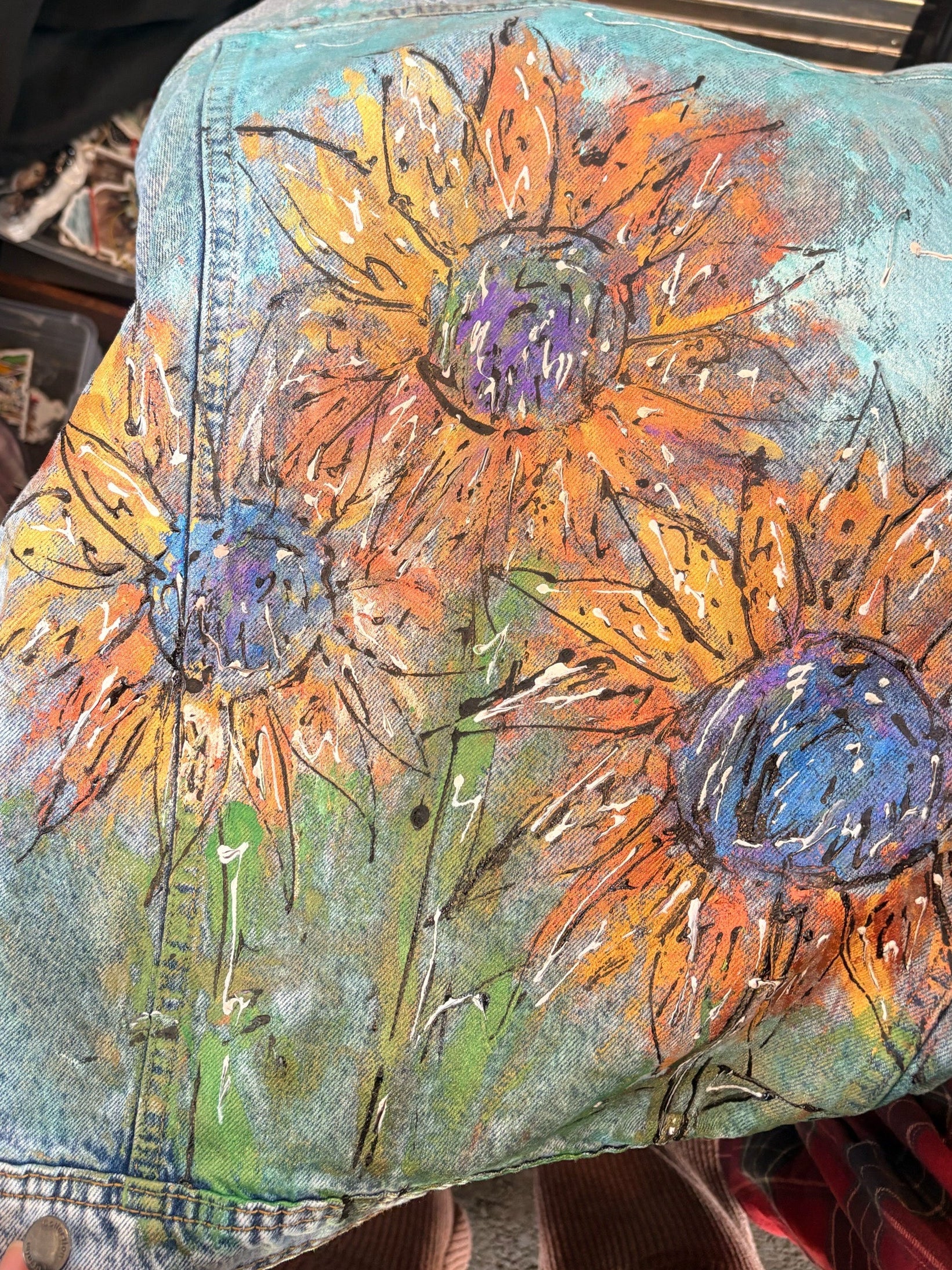 Colorful sunflower design on a denim fabric held by a person.